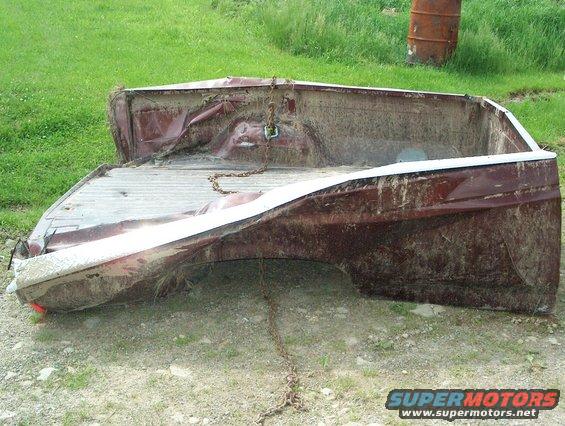 Damaged red pickup truck bed, rear quarter panel view