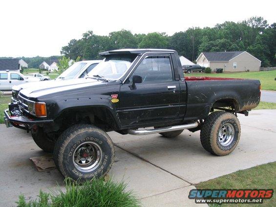 Black lifted pickup truck with aftermarket wheels and tires, side view