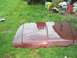1990 Ford F-150 - A maroon car hood rests on a grassy lawn, with various tools and containers scattered nearby.