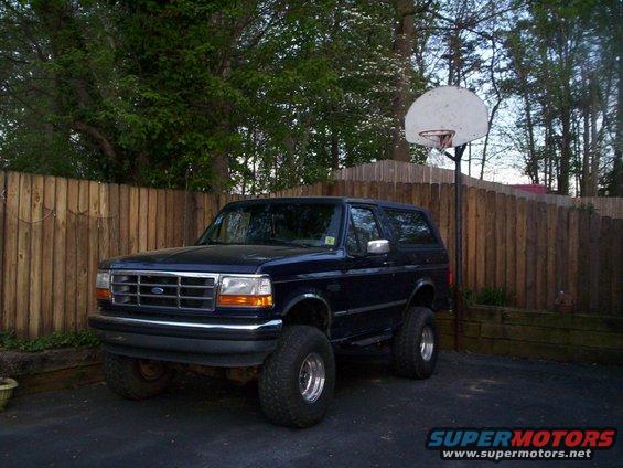 1994 Ford Bronco parked in driveway with wooden fence and basketball hoop