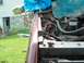 1990 Ford F-150 - The engine bay of a vehicle is partially covered by a blue tarp, with visible hoses and wiring.