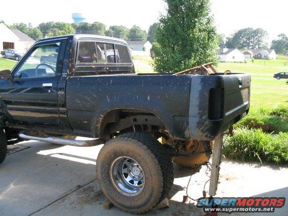 Black pickup truck with rear end removed, sitting on blocks