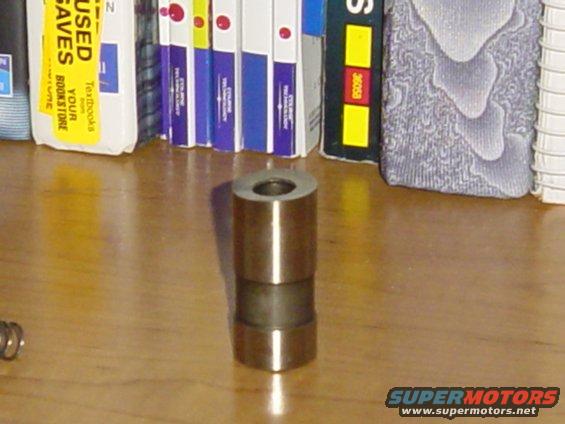 Metal valve stem seal on wooden surface, books in background
