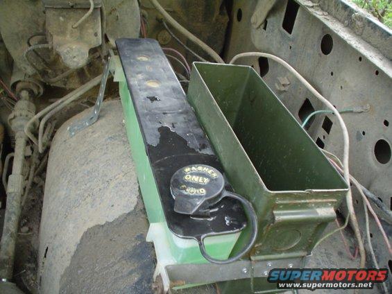 Windshield washer fluid reservoir with a cap that says WASHER ONLY. Also a green metal box next to it