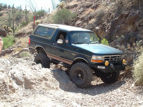 Dark green 1990 Ford Bronco navigating a rocky off-road trail