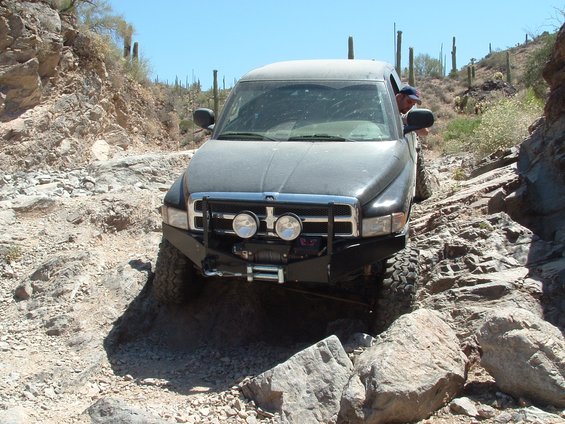 Dark gray Dodge Ram pickup truck driving over rocks on a desert trail