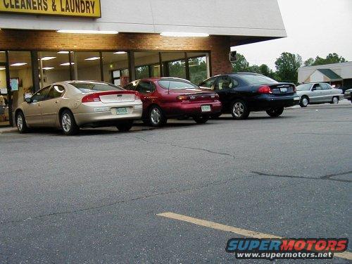 tan sedan, red sedan, and dark blue sedan parked outside a cleaners and laundry