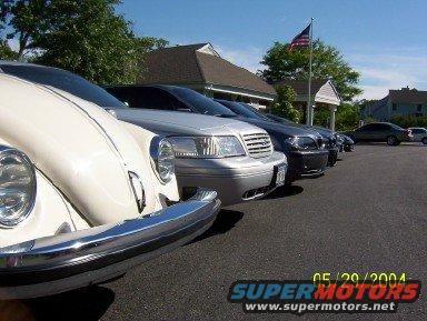 Lineup of cars including a white classic car in the foreground