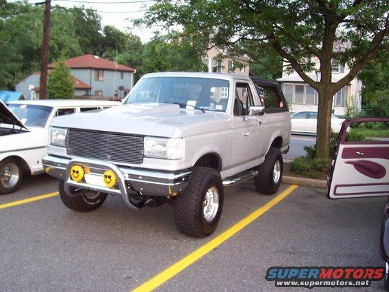 Silver 1990 Ford Bronco 3/4 front view with custom bumper and smiley face lights