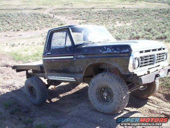 Black flatbed truck with off-road tires and a 1975 grille