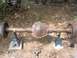 1986 Ford Bronco - This rusty rear axle assembly is supported by jack stands in an outdoor setting.