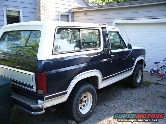 Dark blue and white Ford Bronco parked in driveway, rear quarter view