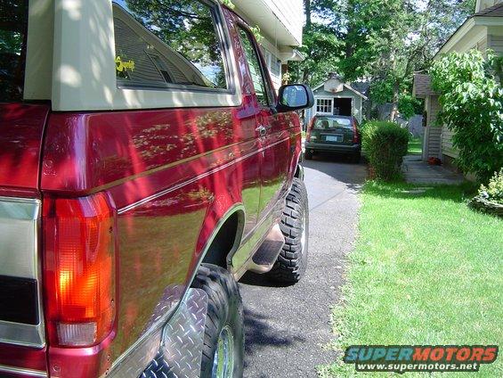 Red 1995 Ford Bronco side view with tan top and lifted suspension