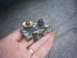 1991 Ford Crown Victoria - A metal bracket with two bolts is held in a hand over a gravel surface.