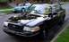 1998 Ford Crown Victoria - A black 1998 Ford Crown Victoria is parked on a residential street next to a blue sedan.
