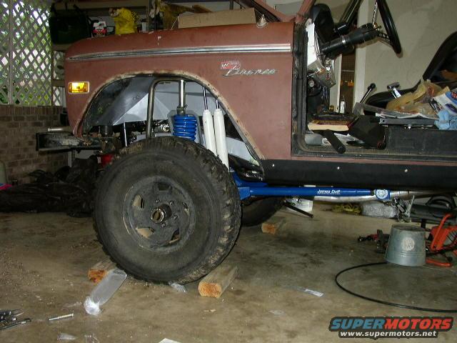 Brown 1974 Ford Bronco in garage, front fender removed, showing suspension modifications
