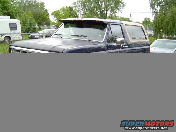 Dark blue Ford Bronco with tan top, parked outside