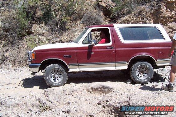 Maroon and white 1992 Ford Bronco side view on rocky terrain