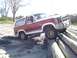 1982 Ford Bronco - A 1982 Ford Bronco navigates an obstacle course made of large logs on a sandy area.