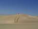1982 Ford Bronco - A lone SUV navigates a sandy terrain under a clear blue sky.