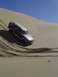 1982 Ford Bronco - A Ford Bronco navigates a steep sand dune under a clear blue sky.