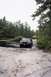 1979 Ford Bronco II - Two SUVs navigate a muddy and watery terrain surrounded by trees and sand.