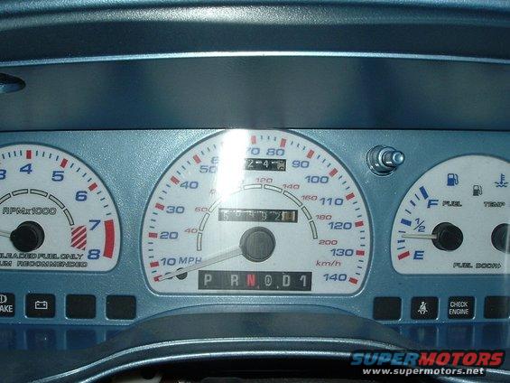 Close-up of a car's dashboard gauges, including speedometer, tachometer, fuel, and temperature gauges