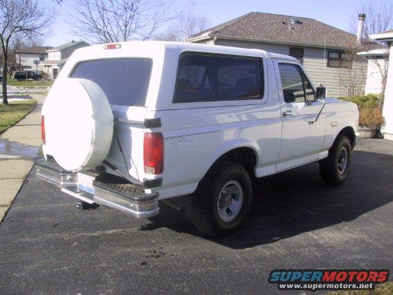 white Ford Bronco parked in driveway, spare tire on back