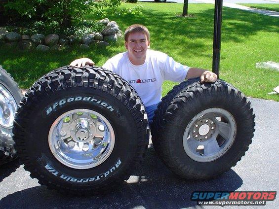 Guy posing with two big BFGoodrich Mud-Terrain T/A tires and rims