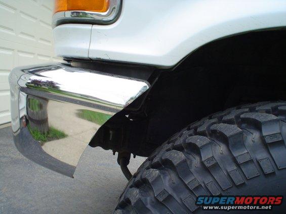 White SUV front corner with chrome bumper and large off-road tire