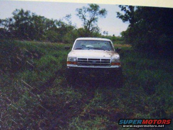 White Ford Bronco stuck in muddy field, front view