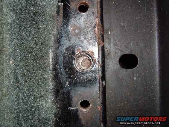 Close-up of a metal bracket with bolt holes and a bolt head