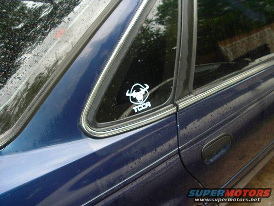 side view of a blue sedan with a TCCA bull sticker on the rear window