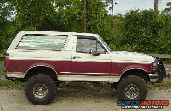 1993 Ford Bronco lifted with large tires, two-tone paint, and brush guard