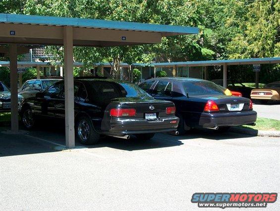 1996 Chevrolet Impala parked next to a dark sedan under a carport