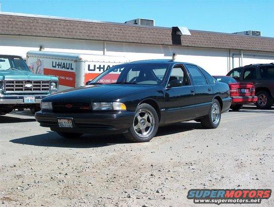 Black 1996 Chevrolet Impala sedan parked on gravel lot, front 3/4 view
