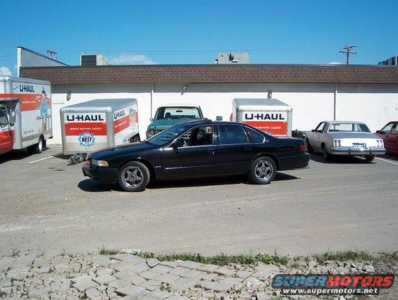 Black 1996 Chevrolet Impala sedan parked next to U-Haul trucks
