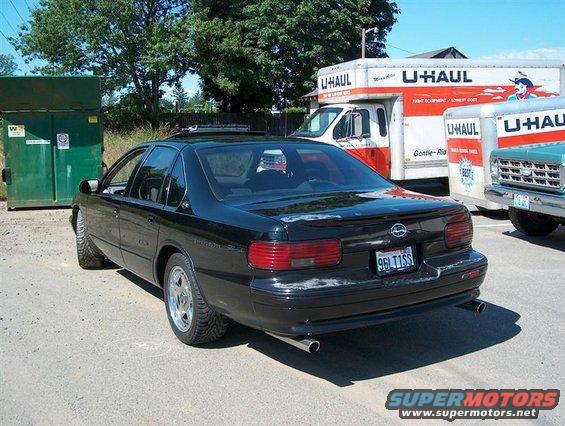 1996 Chevrolet Impala rear view, parked next to U-Haul trucks and a dumpster