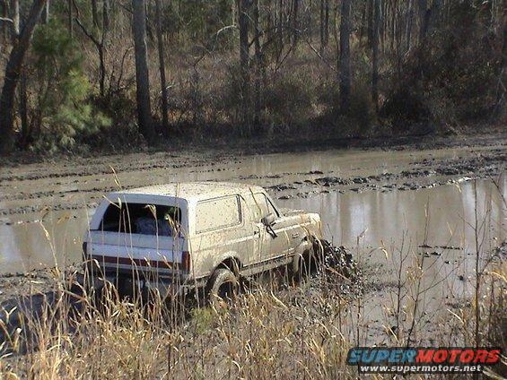 White Ford Bronco stuck in mud, side view