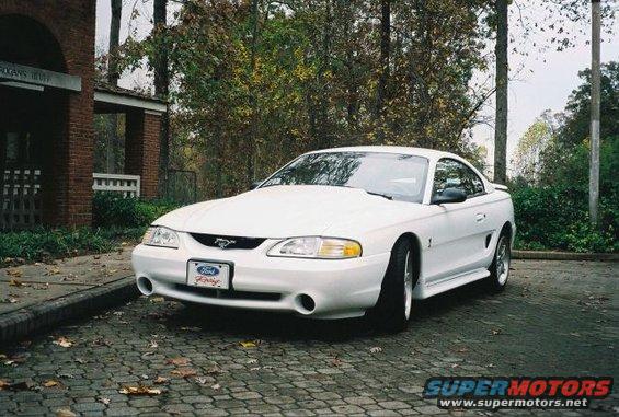 White 1995 Ford Mustang parked on cobblestone driveway
