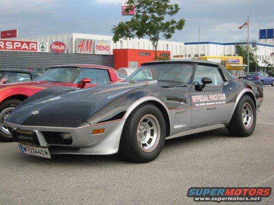 Black and silver Chevrolet Corvette with "OFFICIAL PACE CAR" text, parked outside shops