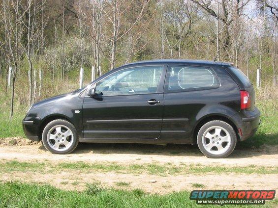 Black 2002 Volkswagen Polo hatchback parked on a dirt road with trees in the background