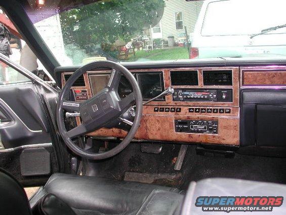 1987 Lincoln Town Car interior showing dashboard with wood grain trim, steering wheel, and radio