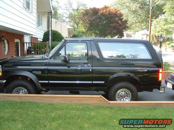 Side view of a black 1993 Ford Bronco parked on grass. Bronco badge visible on fender