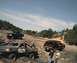 1985 Ford Bronco - Multiple off-road vehicles navigate a challenging dirt terrain on a sunny day.