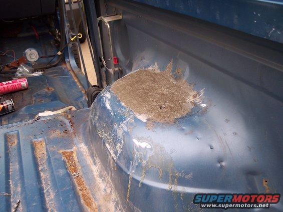 Interior of blue vehicle showing rust and body filler on wheel well