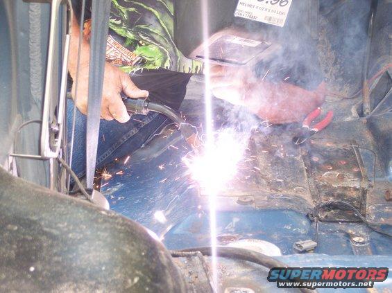 Welding sparks fly inside a blue vehicle's interior