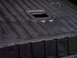 1990 Ford Bronco - Close-up of a dark, textured truck bedliner showing its ribbed surface and a central rectangular opening.