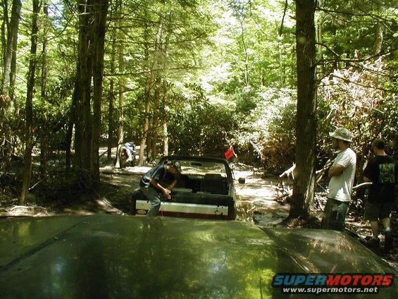 Off-road vehicle stuck in mud with people around
