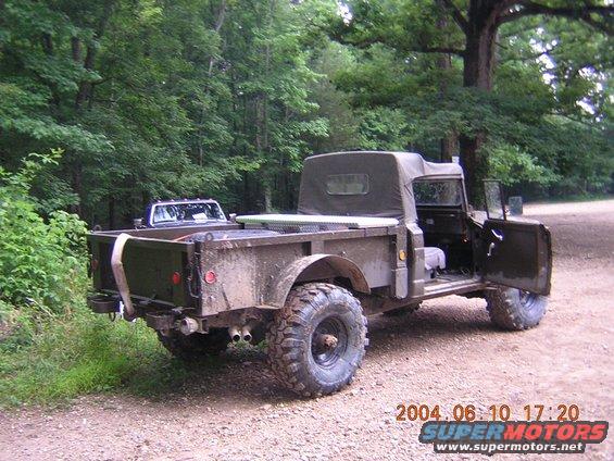 Old military truck parked on a dirt road with another truck behind it